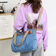 Donna con maglia viola e borsa a tracolla in denim blu, design casual. Moda femminile, accessori trendy, abbigliamento autunnale.
