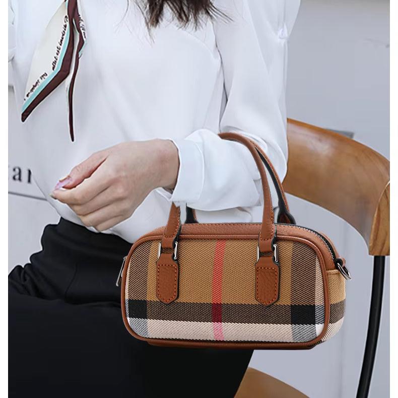 Borsa a mano donna in tessuto a quadri marrone, stile elegante, con manici in pelle, indossata da una persona seduta su una sedia.