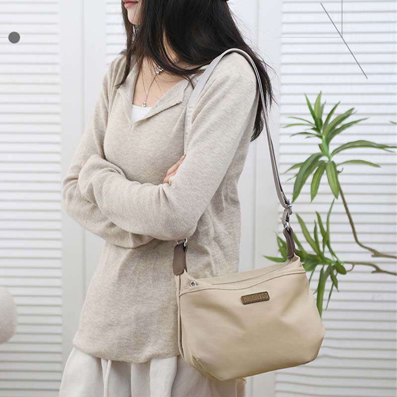 Donna con maglione beige e borsa a tracolla in pelle beige, design elegante e casual. Accessorio moda femminile, perfetto per uso quotidiano.