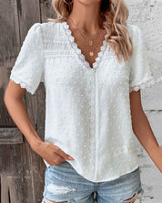 Blusa bianca in pizzo con maniche corte e scollo a V, abbinata a jeans strappati. Moda estiva donna, stile casual chic.