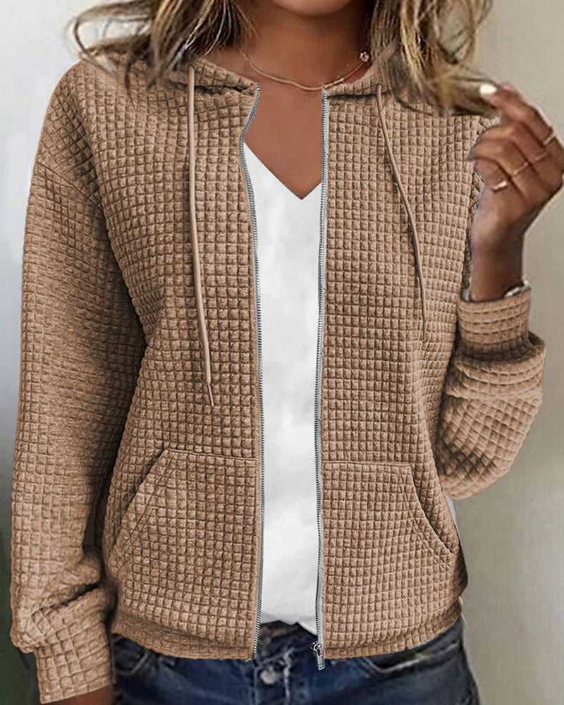Giacca donna beige con cappuccio, tessuto trapuntato, chiusura zip, tasche frontali, abbinata a maglietta bianca. Moda casual autunnale.