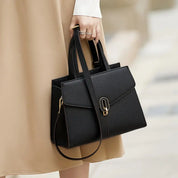 Borsa a mano elegante in pelle nera, design moderno con chiusura dorata, ideale per moda femminile e look professionale. Accessorio di tendenza.