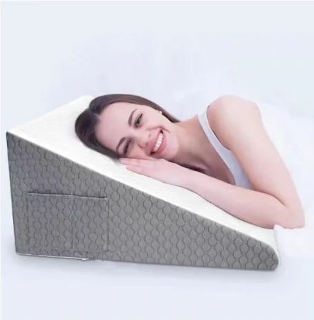 Donna sorridente sdraiata su cuscino a cuneo ortopedico grigio, supporto per schiena e collo, ideale per dormire e relax.
