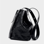 Borsa a secchiello in pelle nera lucida con tracolla regolabile, design elegante e moderno, accessorio moda donna, perfetta per ogni occasione.