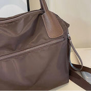 Borsa a tracolla marrone in nylon con cerniera, manici in pelle, design elegante e funzionale, ideale per uso quotidiano e viaggi.