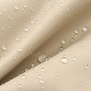 Tessuto impermeabile beige con gocce d'acqua, resistente e idrorepellente, ideale per abbigliamento outdoor e accessori protettivi.