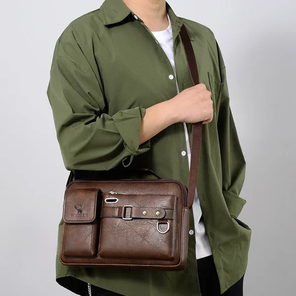 Borsa a tracolla in pelle marrone per uomo, design elegante con tasche multiple, indossata su camicia verde. Accessorio moda maschile versatile.