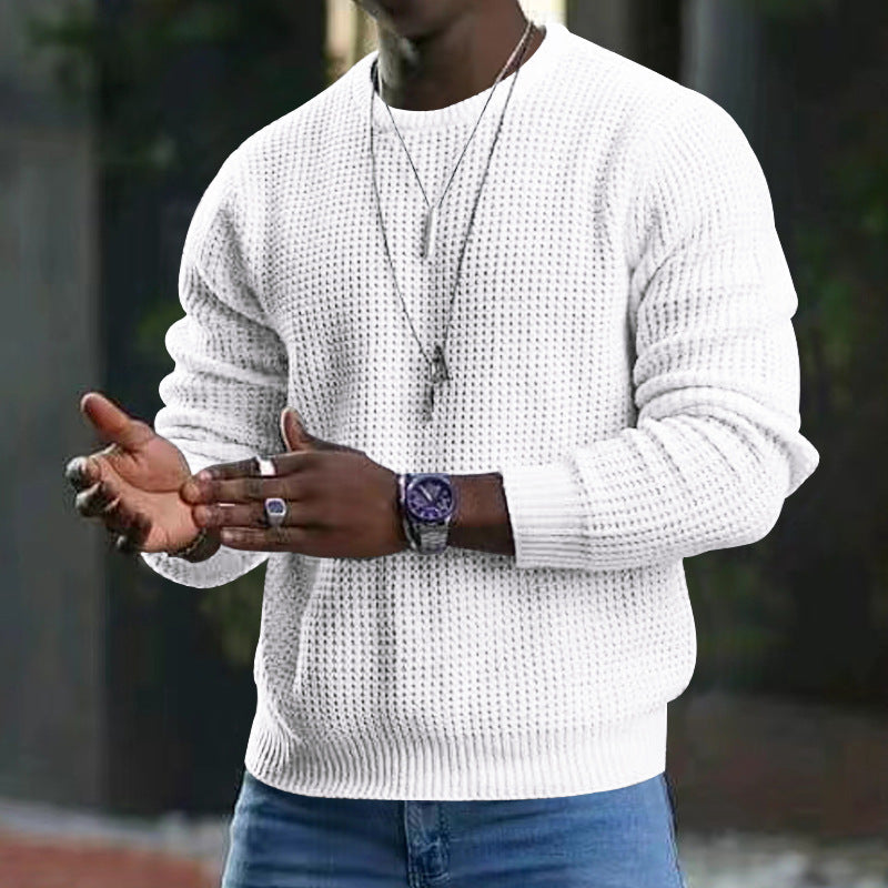 Maglione bianco a maglia grossa da uomo, indossato con jeans blu. Accessori: orologio nero, collana e anello. Moda casual autunnale.