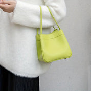 Borsa a tracolla verde lime in pelle, indossata da una persona con cappotto bianco. Accessorio moda elegante e moderno per donna.