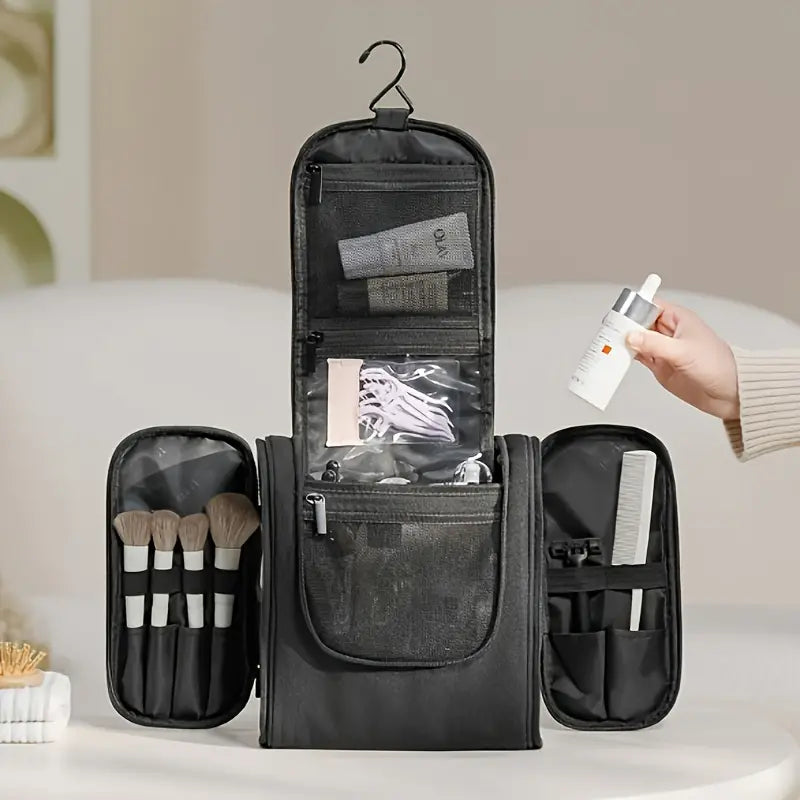 Borsa da toilette nera aperta con gancio, scomparti per pennelli trucco, flaconi e accessori. Ideale per viaggi e organizzazione cosmetici.
