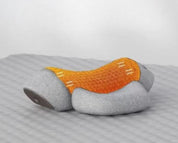 Cuscino massaggiante ergonomico grigio e arancione su superficie ondulata, design moderno per supporto cervicale e relax.