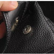 Portafoglio in pelle nera con chiusura a bottone, texture granulosa, design elegante e resistente, accessorio moda uomo e donna.