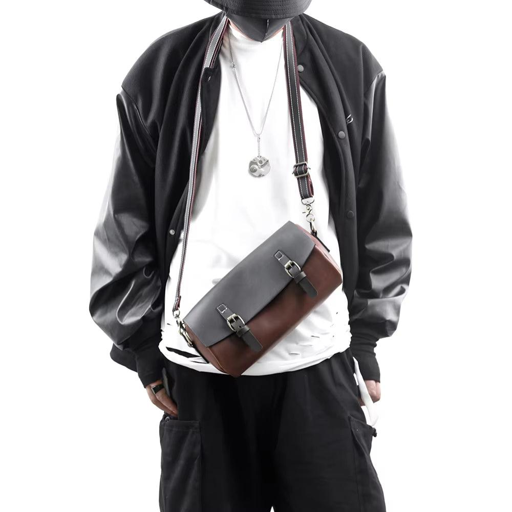 Uomo con giacca nera e borsa a tracolla in pelle bicolore, stile casual urbano. Accessorio moda maschile, tendenza streetwear.