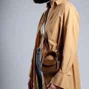 Cappotto beige lungo, borsa a tracolla marrone in pelle, maglione grigio, jeans blu. Moda donna autunno, stile casual chic.