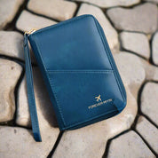 Portafoglio da viaggio blu in pelle con cerniera, design elegante, scritta "Forever My In", su sfondo di pietre. Accessorio moda uomo/donna.