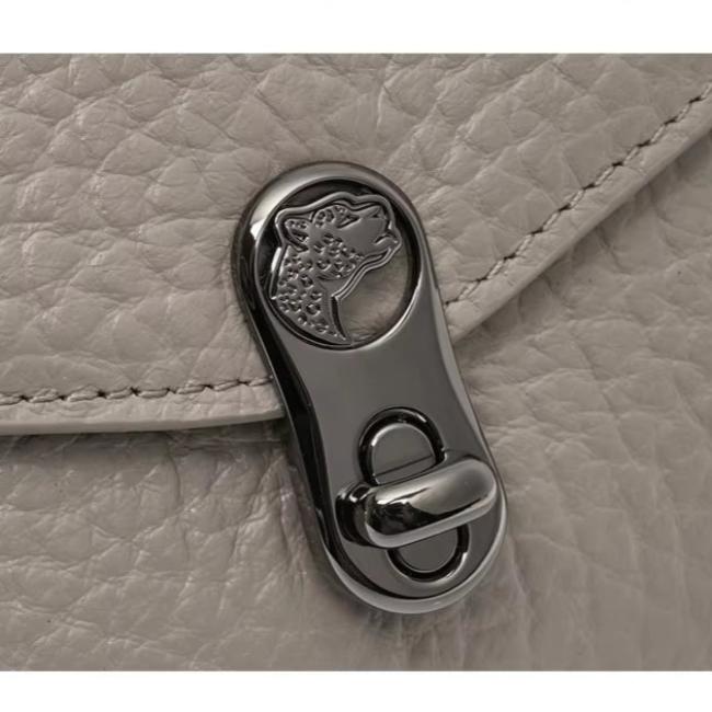 Chiusura in metallo lucido con incisione leopardo su borsa in pelle grigia. Accessorio moda elegante, dettagli di lusso, design raffinato.