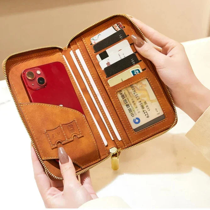 Portafoglio in pelle marrone con zip, contenente uno smartphone rosso, carte di credito e documenti. Design elegante e funzionale per organizzazione quotidiana.