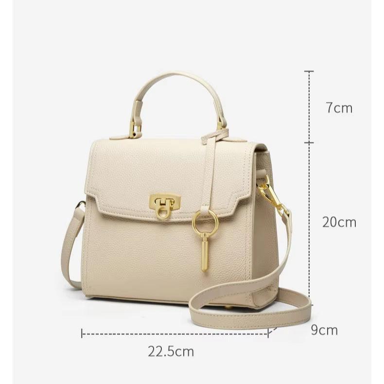 Borsa a tracolla beige in pelle, dimensioni 22.5x9x20 cm, con manico superiore, chiusura a scatto dorata e ciondolo chiave. Elegante e versatile.