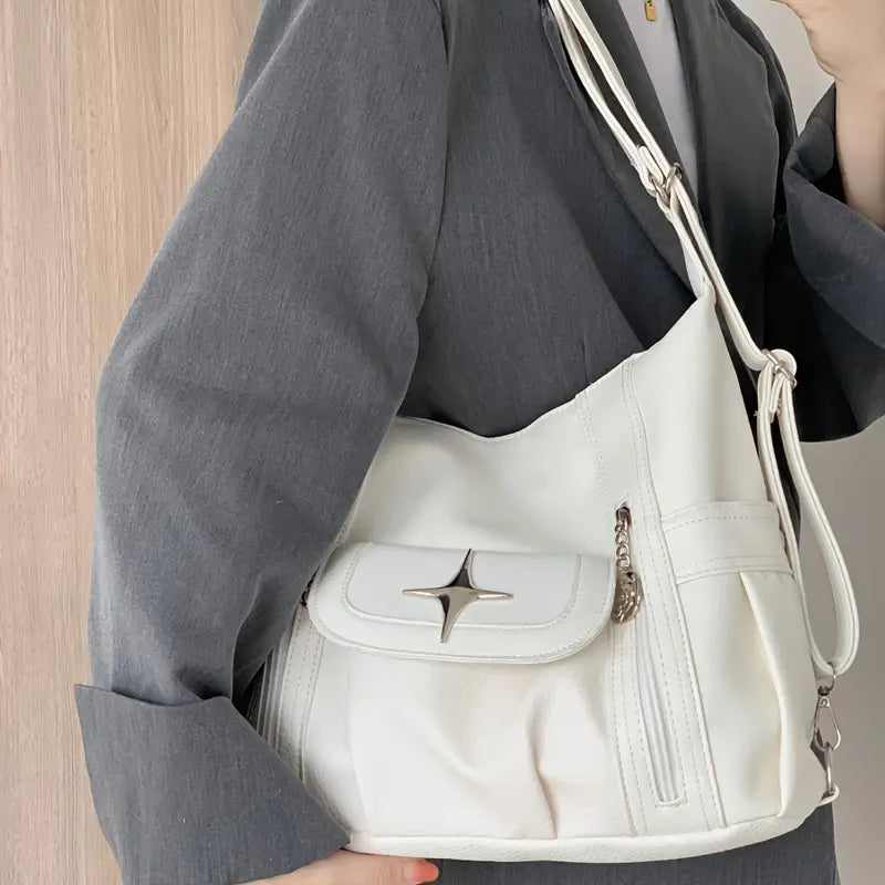 Borsa a tracolla bianca elegante con tasca frontale e chiusura a stella, indossata da una persona in giacca grigia. Accessorio moda donna.