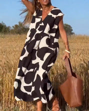 Donna in abito lungo bianco e nero astratto, campo di grano, borsa marrone, estate, moda casual, stile boho chic, giornata soleggiata.