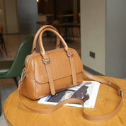 Borsa a mano in pelle marrone su tavolo di legno, design elegante con tracolla regolabile, perfetta per moda donna e accessori di lusso.