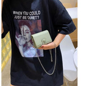 Maglietta nera con stampa artistica e borsa a tracolla verde chiaro. Moda casual, accessori trendy, abbigliamento streetwear.
