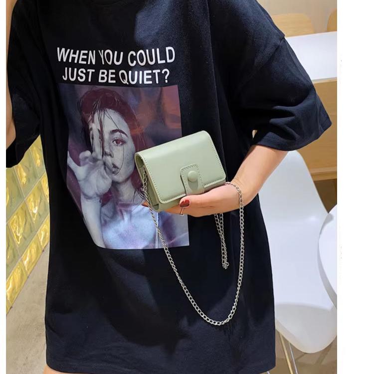 Maglietta nera con stampa artistica e borsa a tracolla verde chiaro. Moda casual, accessori trendy, abbigliamento streetwear.