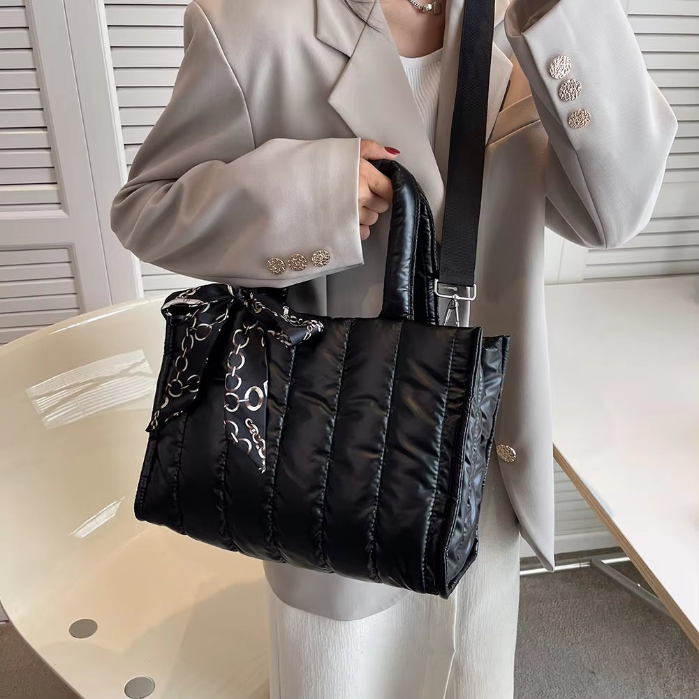 Borsa a tracolla nera trapuntata in nylon, indossata da una persona con giacca beige. Accessorio moda elegante, perfetto per l'autunno.