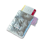 Porta documenti argento con motivo floreale, contenente biglietti colorati. Accessorio elegante e funzionale per viaggi e organizzazione documenti.