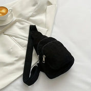 Zaino a tracolla nero su letto bianco con tazza di caffè. Design elegante, ideale per moda urbana e viaggi. Accessorio versatile e pratico.