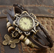 Orologio vintage con cinturino in pelle intrecciata, quadrante antico e ciondolo a farfalla. Design retrò, accessorio moda elegante.