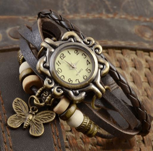 Orologio vintage con cinturino in pelle intrecciata, quadrante antico e ciondolo a farfalla. Design retrò, accessorio moda elegante.