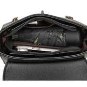 Interno di una borsa in pelle nera con ombrello pieghevole e smartphone. Accessori moda, borsa donna elegante, organizzazione pratica.