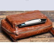 Borsa a tracolla in pelle marrone con cerniera aperta, mostra smartphone e portafoglio all'interno. Design elegante, ideale per uomo e donna.