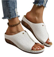 Sandali donna bianchi con zeppa in legno, motivo coccodrillo, indossati con jeans strappati. Scarpe estive eleganti e comode.