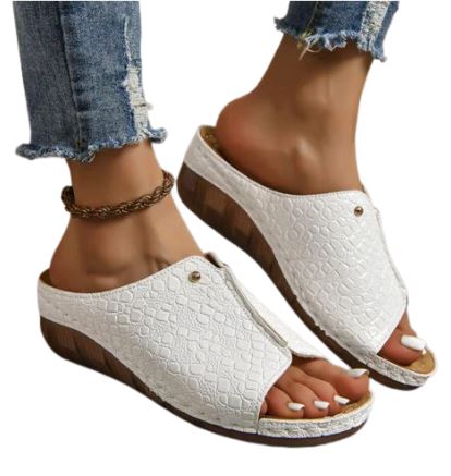 Sandali donna bianchi con zeppa in legno, motivo coccodrillo, indossati con jeans strappati. Scarpe estive eleganti e comode.