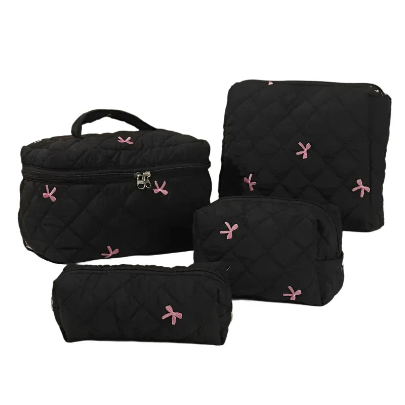 Set di borse da viaggio nere trapuntate con fiocchi rosa, include borsa grande, pochette, astuccio e borsa per cosmetici. Elegante e funzionale.