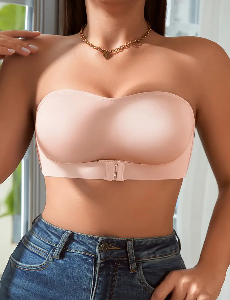 Reggiseno senza spalline color nude, design liscio, chiusura frontale, indossato con jeans. Intimo femminile elegante e confortevole.