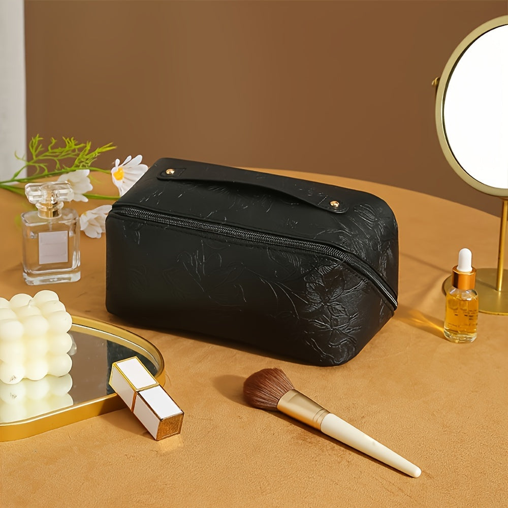 Elegante borsa trucco nera su tavolo con specchio, pennello, profumo e fiori. Accessori cosmetici, organizzazione bellezza, design moderno.