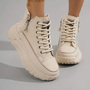 Scarpe da ginnastica alte bianche con suola spessa, lacci e cerniera laterale. Design moderno e trendy, perfette per look casual e sportivi.