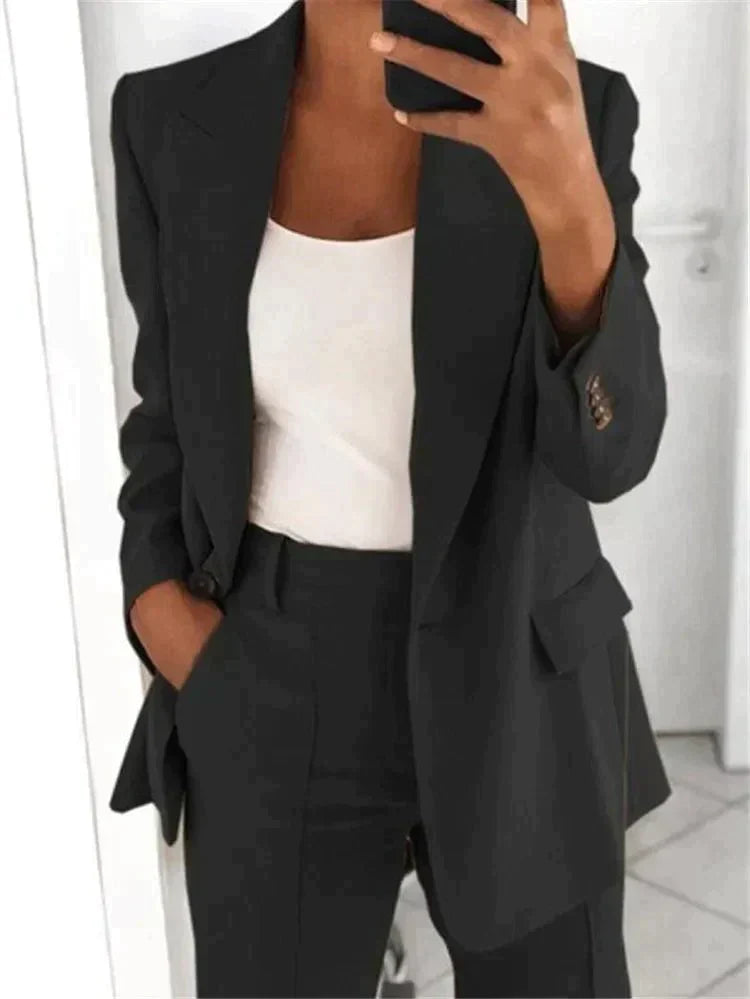 Donna in abito elegante nero, giacca e pantaloni, con top bianco. Moda business casual, outfit professionale per ufficio.