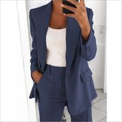 Donna in abito elegante blu, giacca e pantaloni coordinati, con top bianco. Moda femminile, abbigliamento formale, stile business casual.
