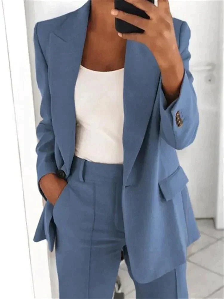 Completo donna elegante blu, giacca e pantaloni abbinati, indossato con top bianco. Moda femminile, abbigliamento formale, stile business casual.