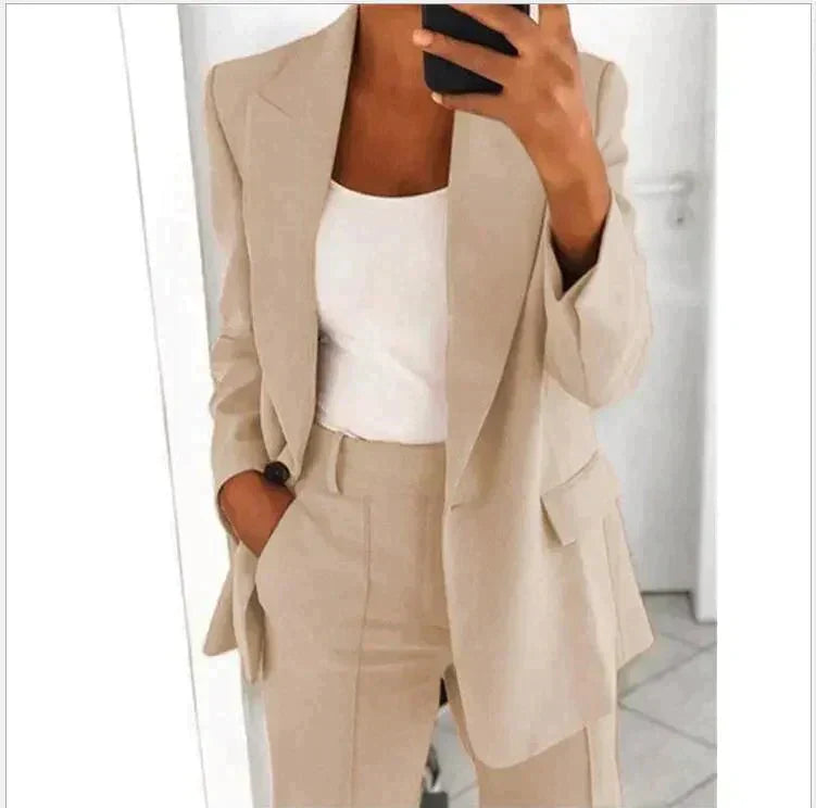 Donna in abito elegante beige, giacca e pantaloni coordinati, con top bianco. Moda donna, abbigliamento formale, stile business casual.