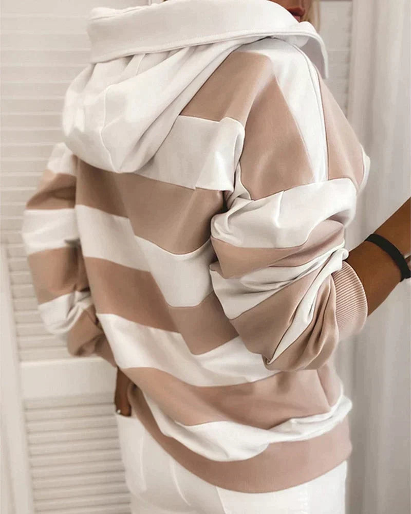 Felpa a righe bianche e beige, con cappuccio, indossata da una persona di spalle. Moda casual, abbigliamento autunnale, stile urbano.