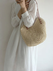 Donna con abito bianco indossa borsa a tracolla in paglia intrecciata, stile estivo, moda casual, accessorio leggero e naturale.