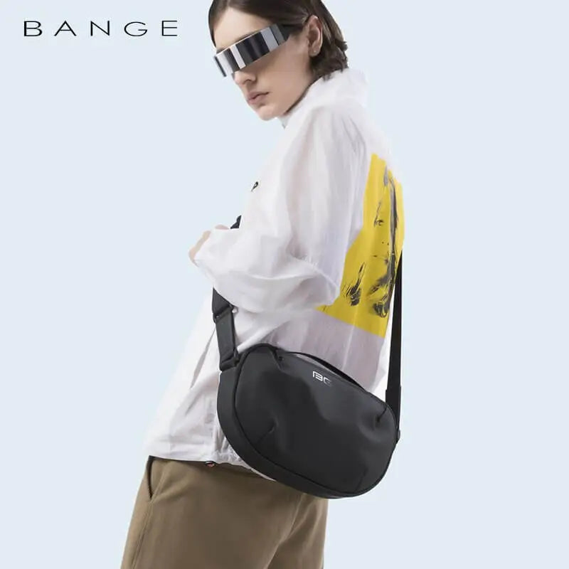 Giovane con occhiali futuristici indossa borsa a tracolla nera Bange, camicia bianca con stampa gialla. Moda urbana, accessori trendy.