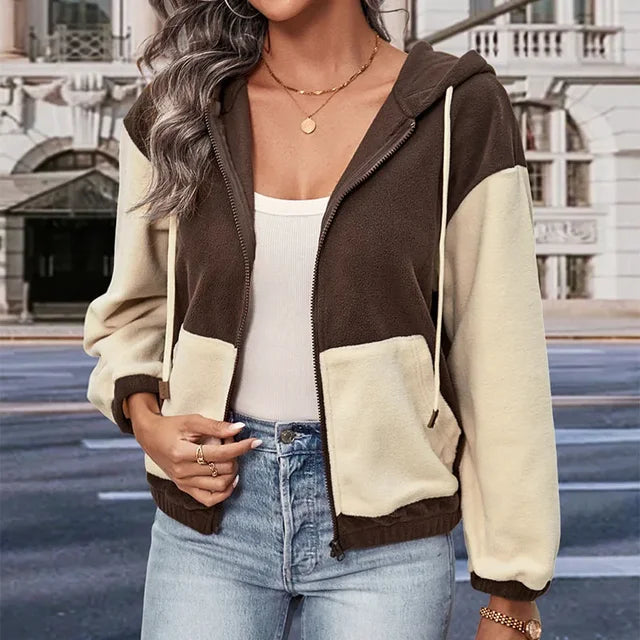 Giacca con cappuccio bicolore marrone e beige, indossata da donna con top bianco e jeans. Moda casual autunnale, stile urbano.