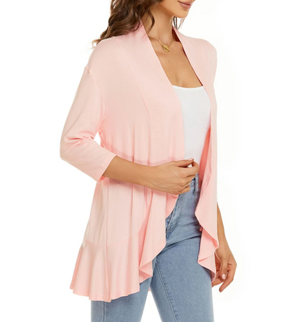 Donna con cardigan rosa chiaro, maniche a tre quarti, indossa top bianco e jeans. Moda femminile casual, abbigliamento primaverile elegante.