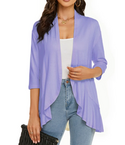 Donna con cardigan aperto viola, maniche a tre quarti, indossa top bianco e jeans. Accessori: collana oro, borsa nera. Moda casual elegante.
